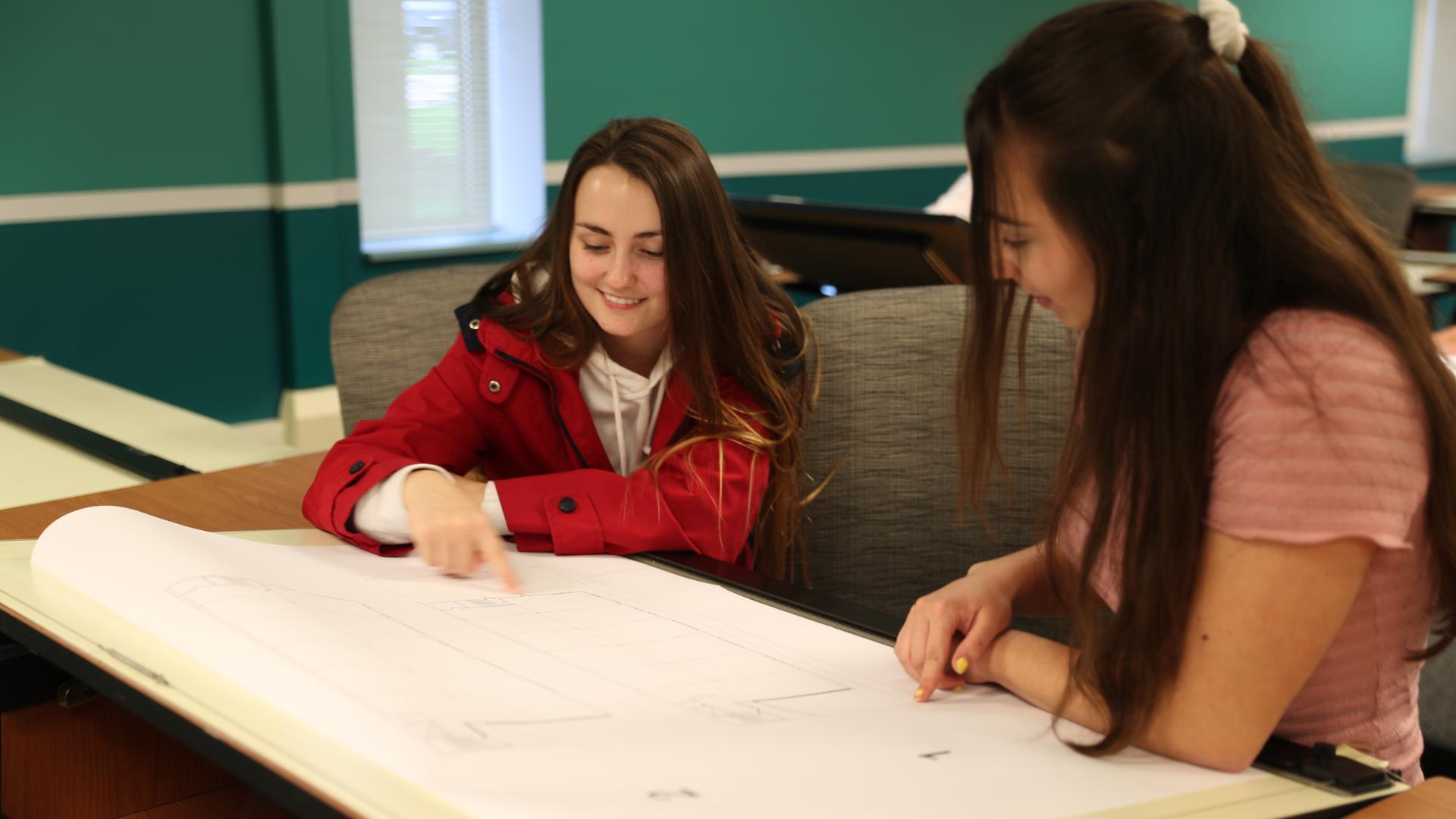 two female students look over blueprints