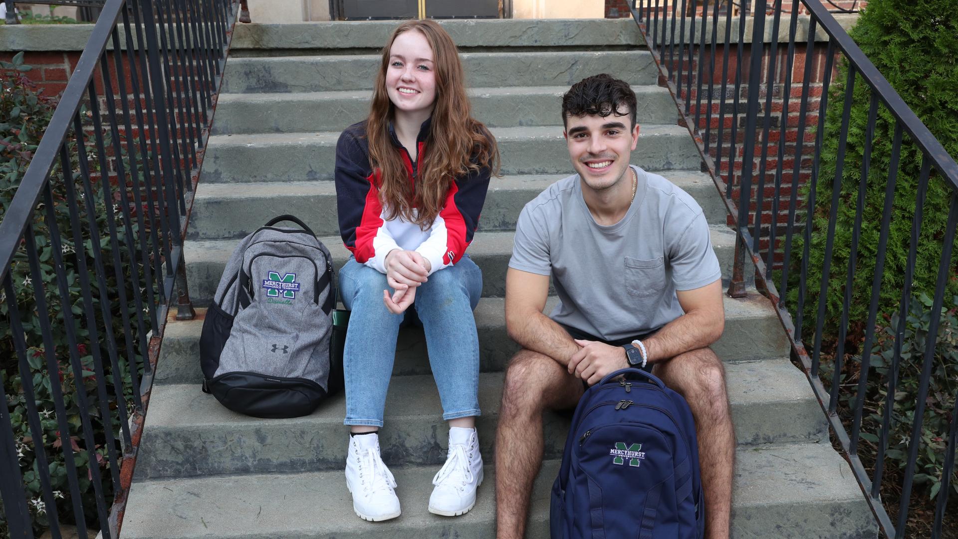 male and female student sit on outdoor stairs with backpacks