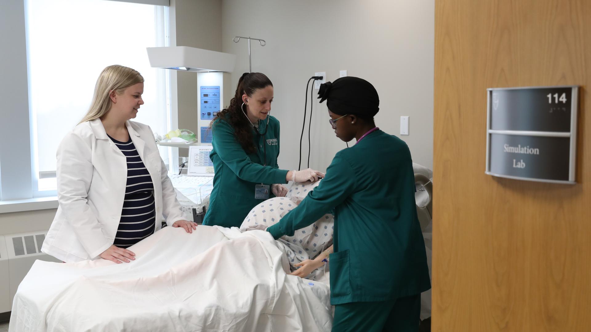 two female nursing students and an instructor practice in a simulation lab