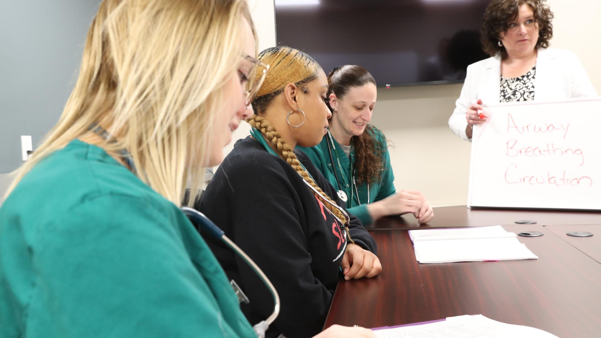 Nursing students and professor working at a classroom table.
