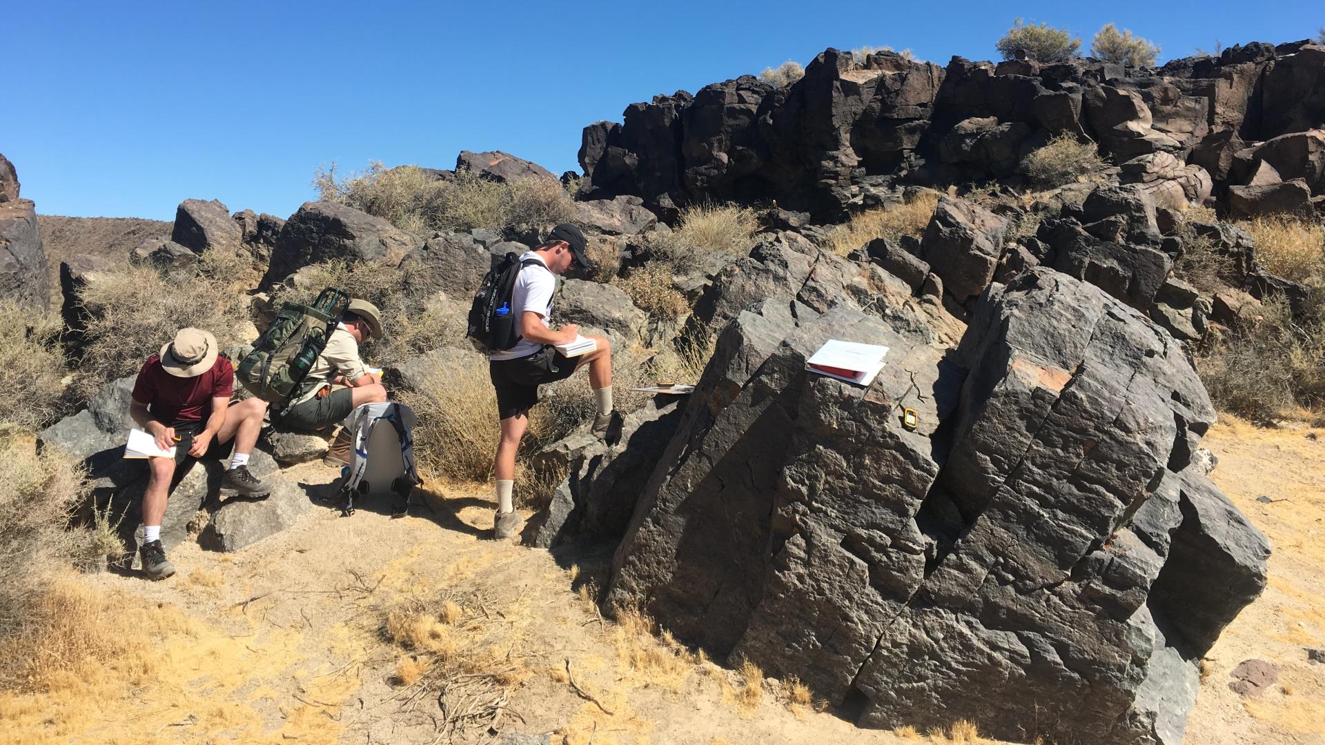 three geology students research in the desert