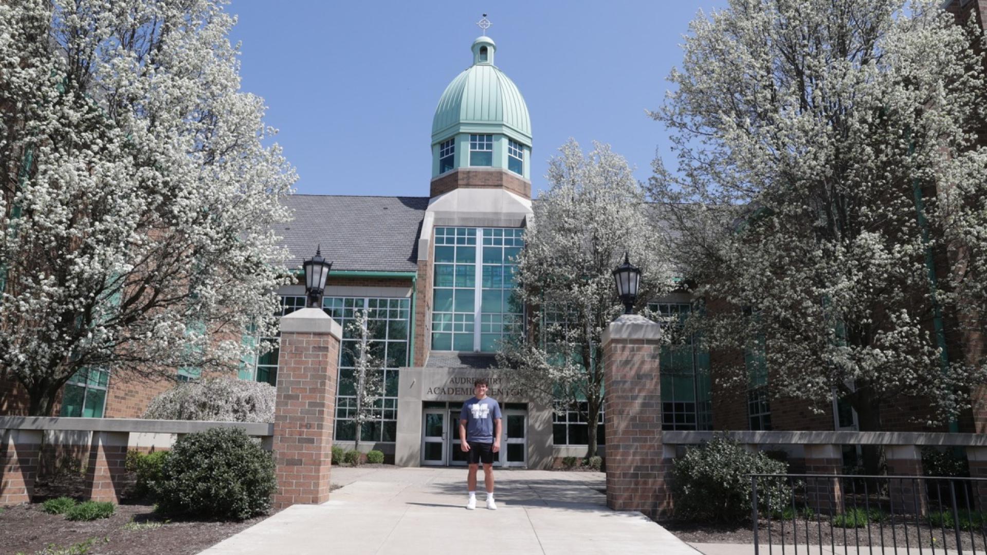 Student in front of Audrey Hirt building