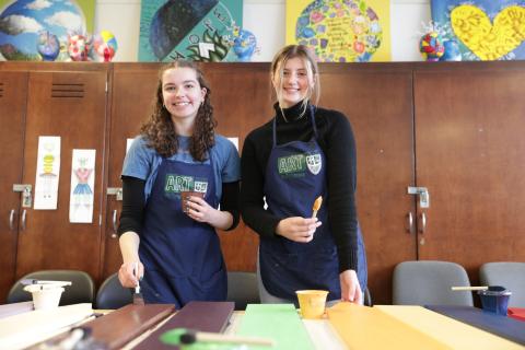 two female art students pose while painting