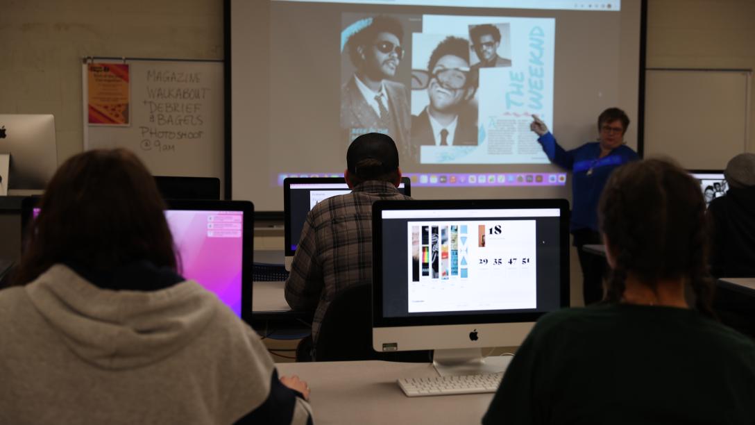 a professor instructs a class of graphic design students