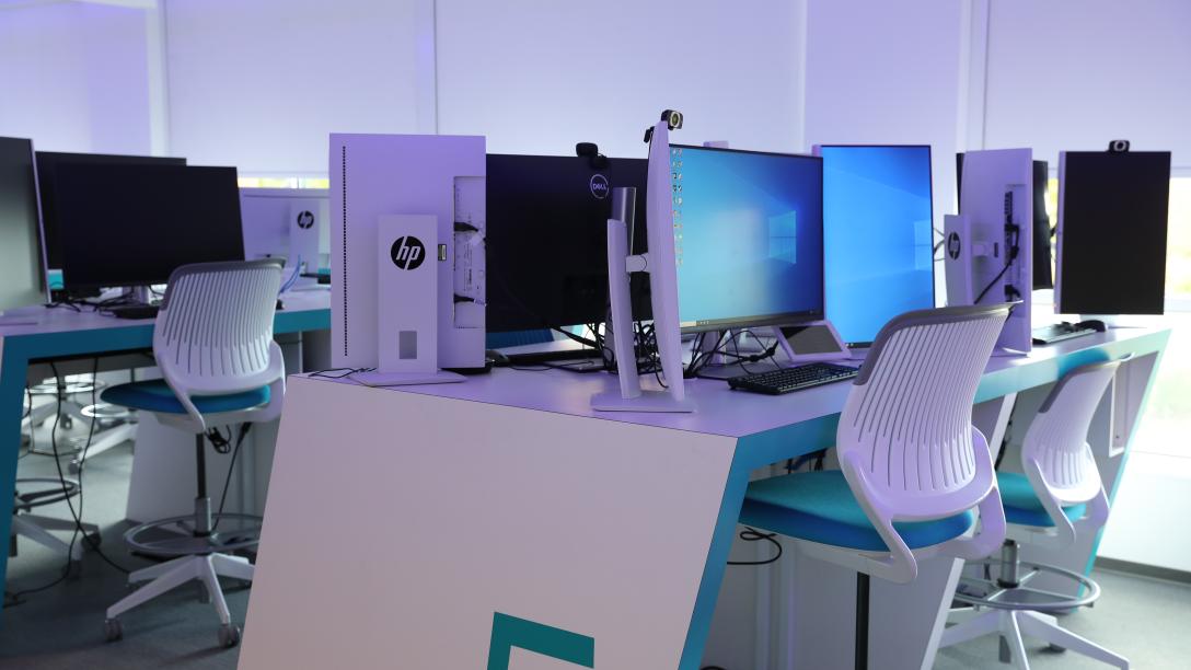 tables and chairs with desktop computers in a cyber lab
