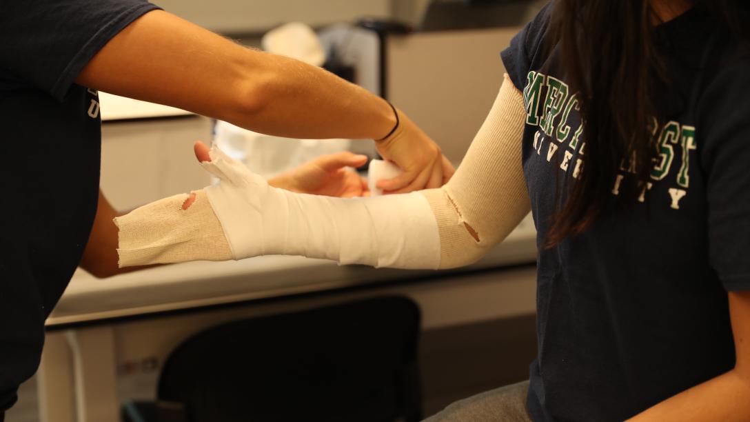 two students learn how to properly apply casts on arms