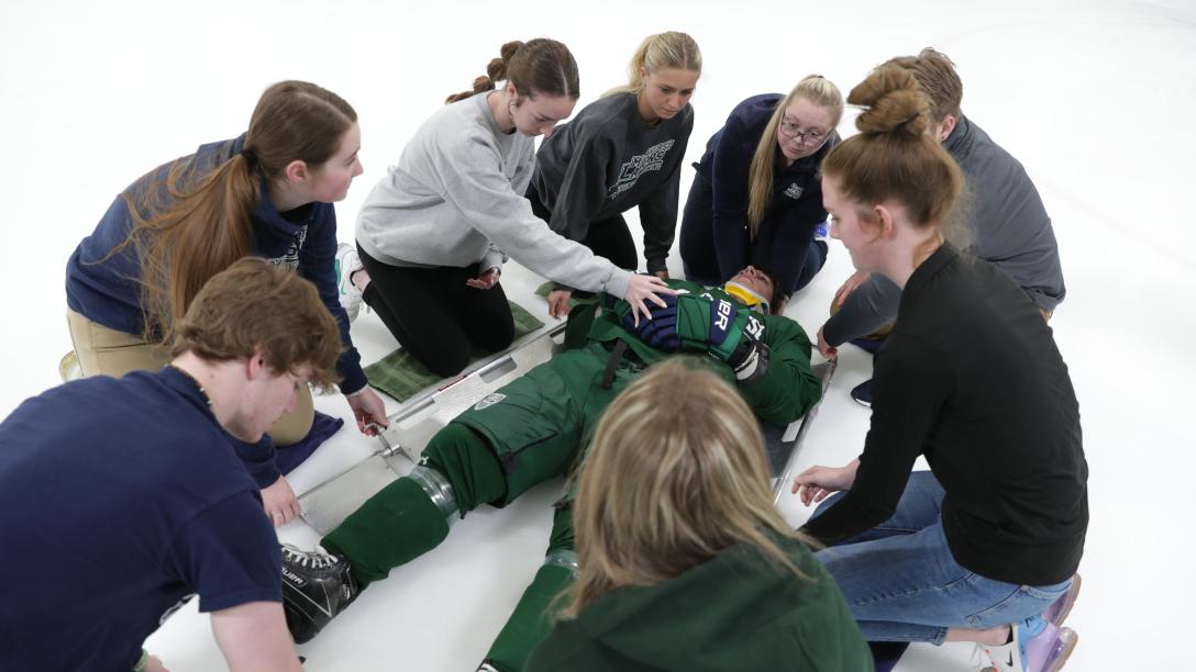 students gather around and examine injured hockey player