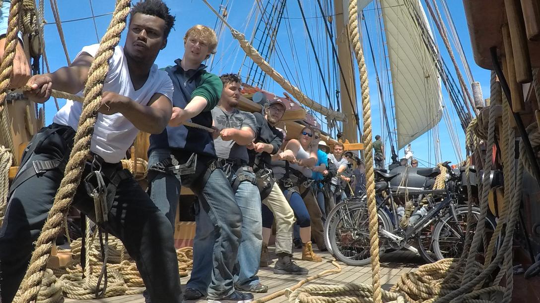 a group of students hoist a ship's sail