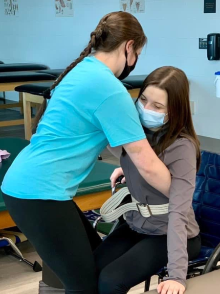 a physical therapist assistant helps a patient out of a wheelchair