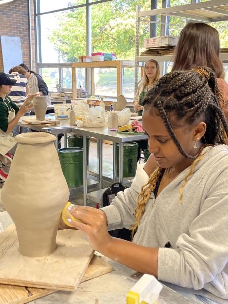 a female student creates a clay vase