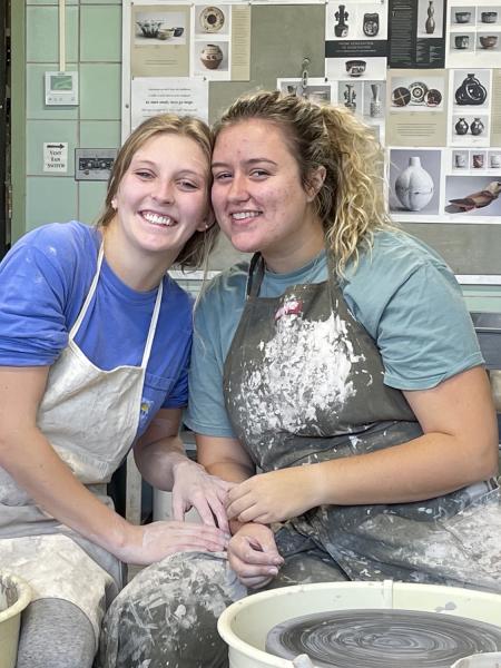 two female students at a pottery wheel