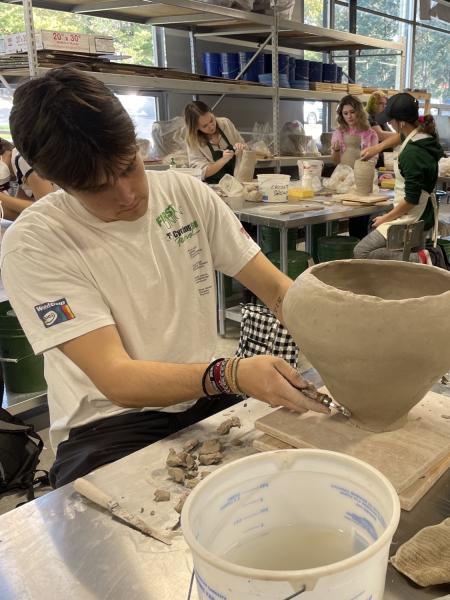 male art student creates a clay pot